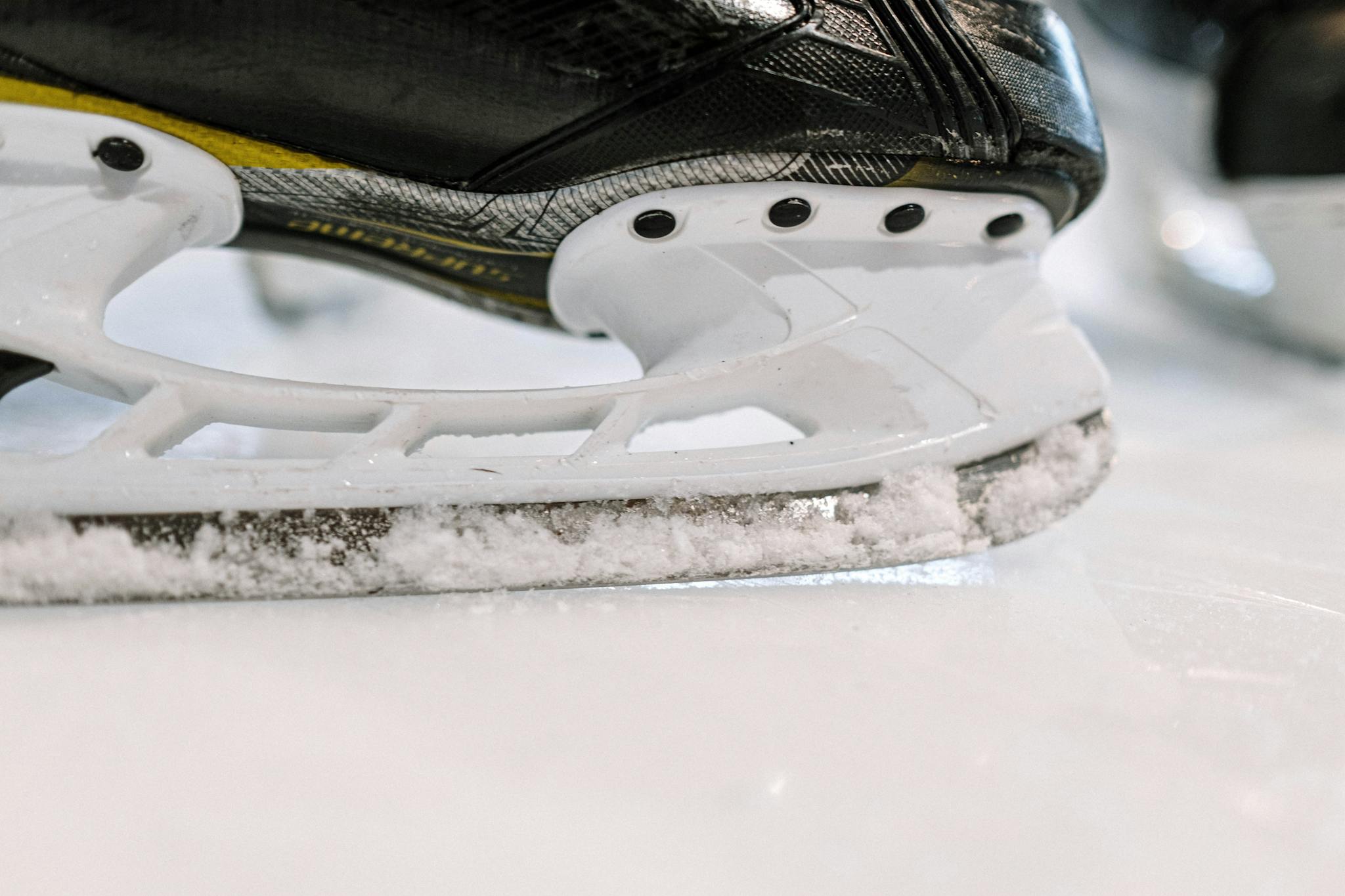 Detailed shot of an ice hockey skate blade gliding over ice, perfect for winter sports content.