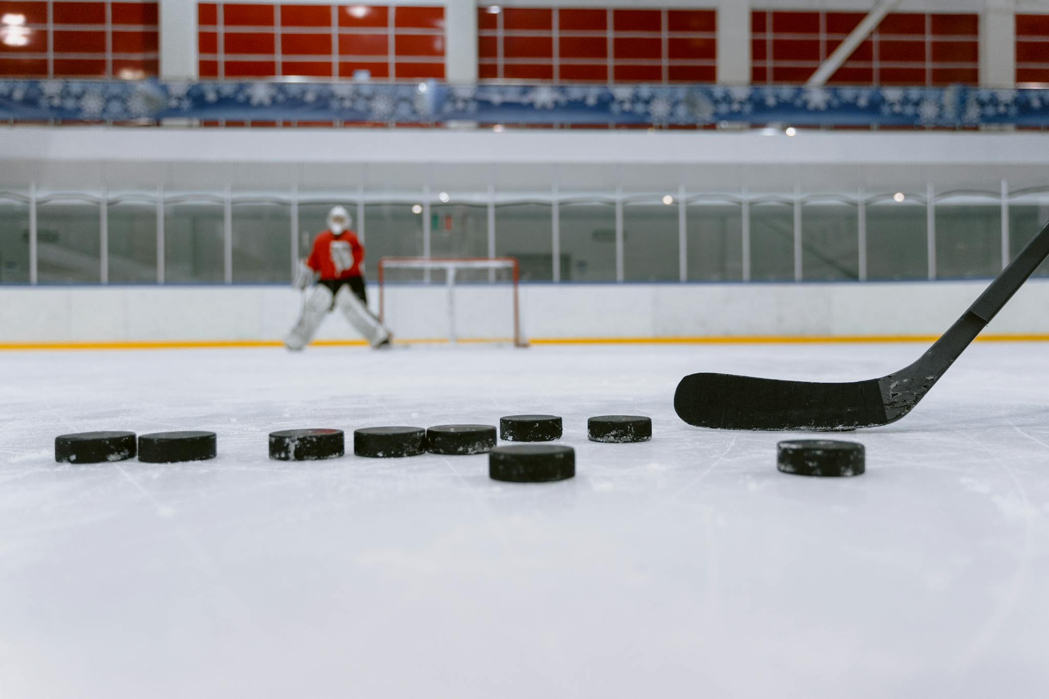 Exciting ice hockey scene with player, pucks, and goal indoors.